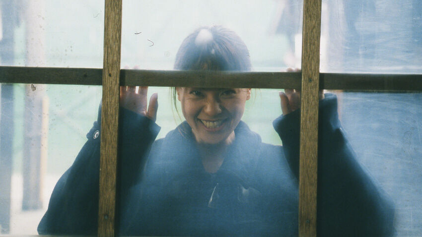 A Lady Stares Menicingly Through A Window