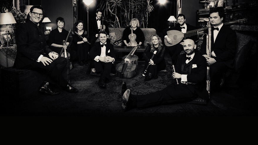 A black and white photo of ten members of La Nuova Musica, sitting around a room with their instruments