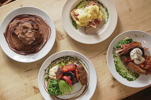 Four plates of delicious food sit atop a wooden table