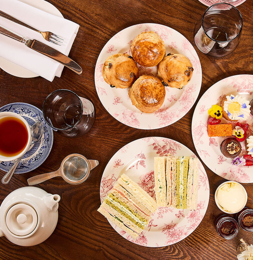 A table full of sandwiches, scones, cakes and a cup of tea