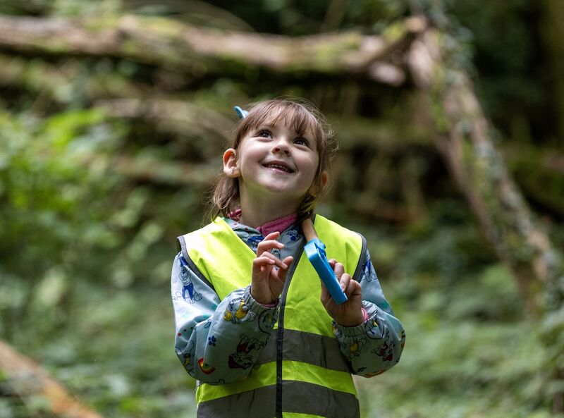 A young child in a high vis vest in nature