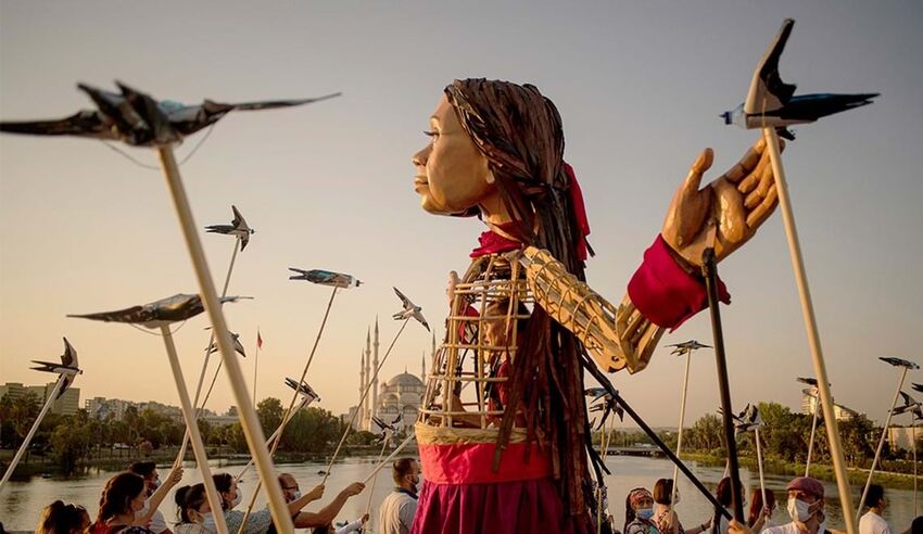 A giant puppet of The Girl From Aleppo, surrounded by puppet seaguls on sticks
