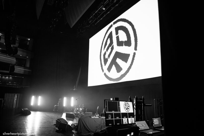 Black and white photo of an empty stage with a logo containing the letters ADF projected onto a white screen above