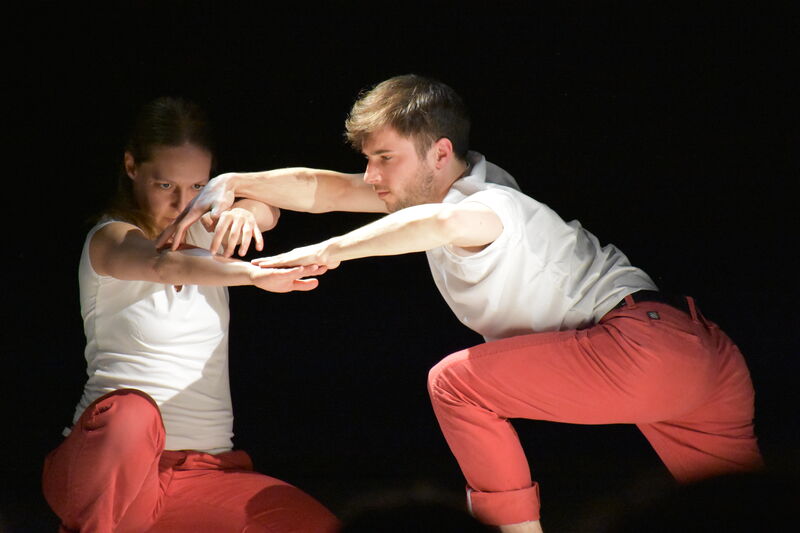 Two performers with their arms overlapping