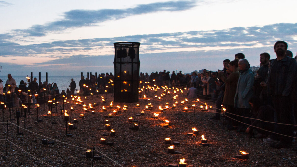 Candlelight installation by Brighton beach surrounded by onlookers.