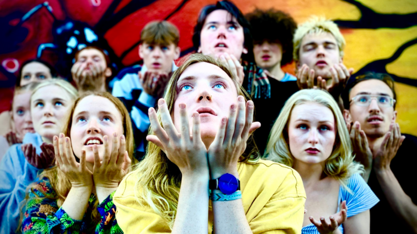 Individuals posed for a group photo posing with their hands beneath their chins