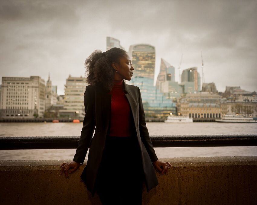 Natasha Brown stands in front of the River Thames, with the London skyline behind her