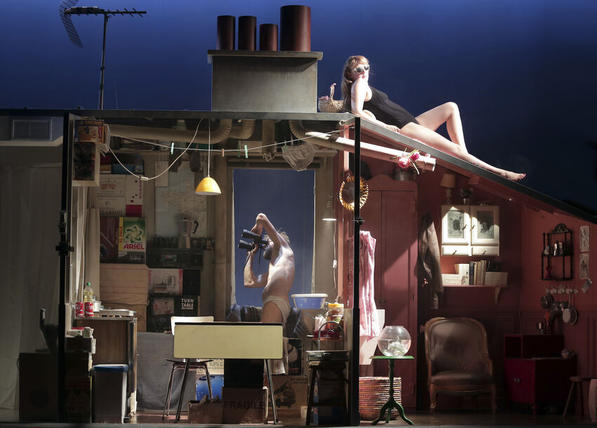 A set of the inside of a house, a person leans out the windo, while another sides in a swimming costume on top of the roof