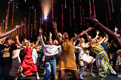 A group of people are dancing with their arms in the air