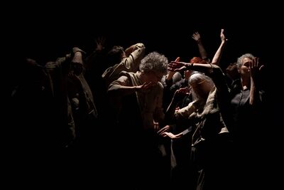 Group of performers moving in low light against a black background