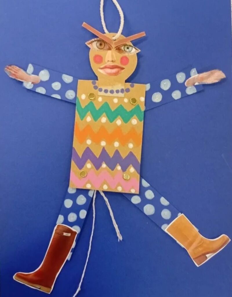 A handmade puppet sits on a blue background