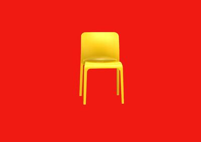 A yellow plastic chair on a red background