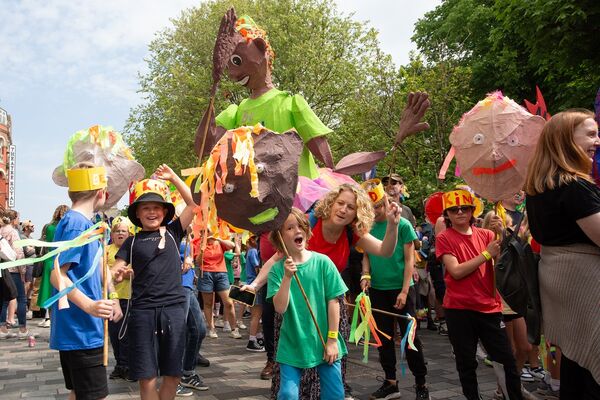 A group of children holding papier mache sculptures of people