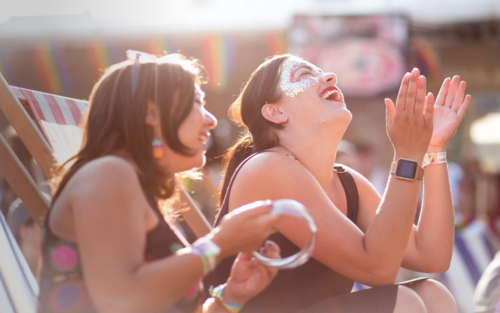 Two girls sitting on deckchairs, smiling and dancing