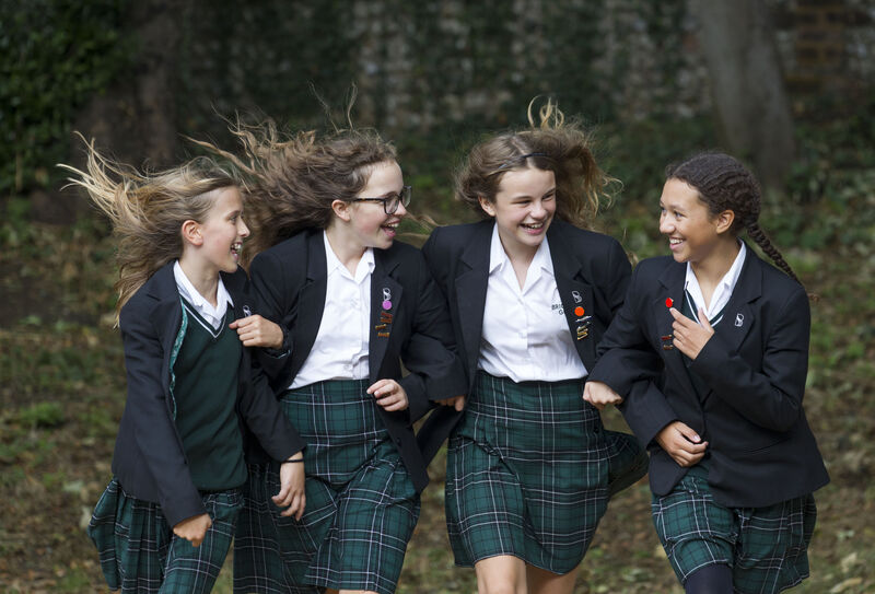 Four girls linking arms, laughing all wearing school uniform