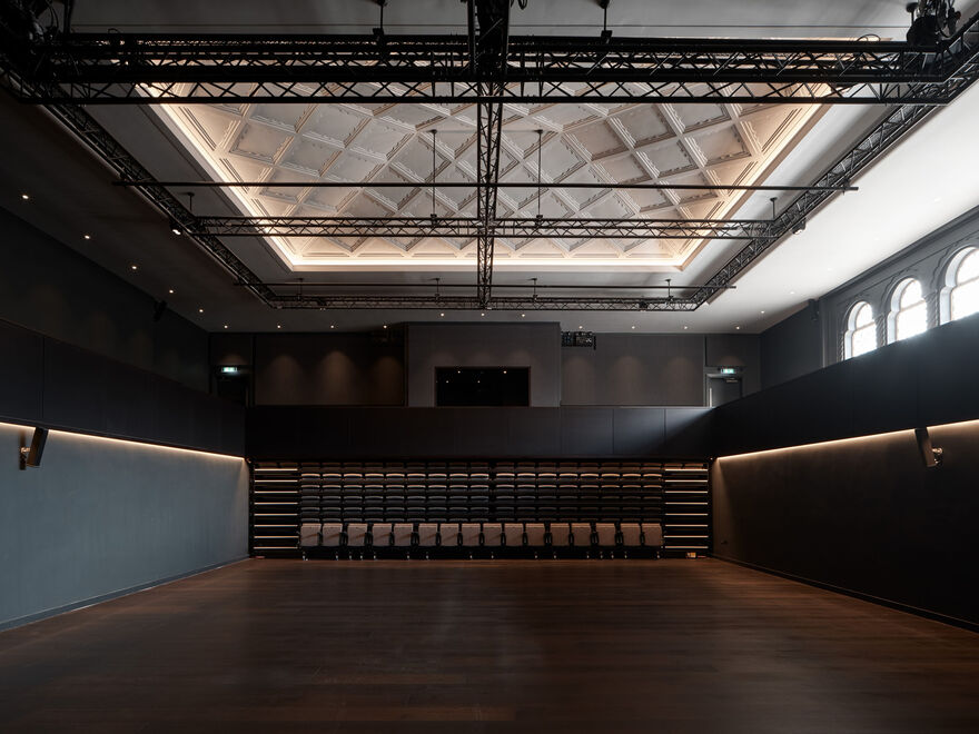 Interior of Studio Theatre, showing a view of an empty room with raked seating pushed to the back of the room