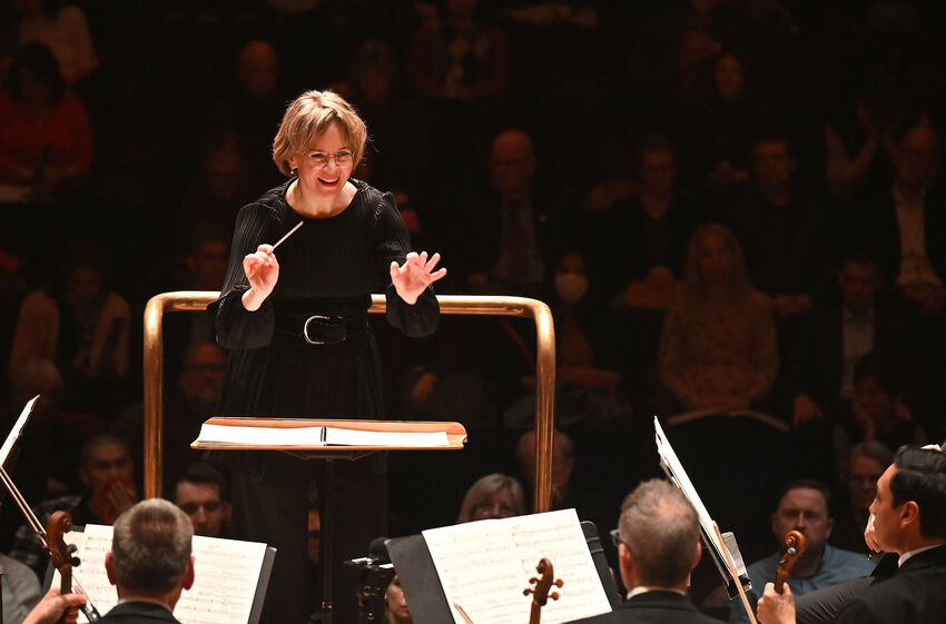 Susanna Mälkki conduction an orchestra with a smile on her face