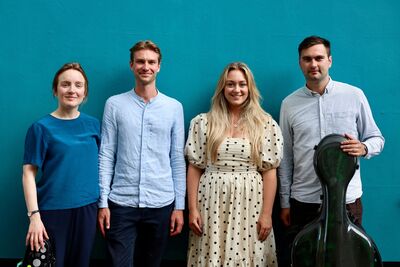 Minerva Baroque standing in front of a blue wall smiling