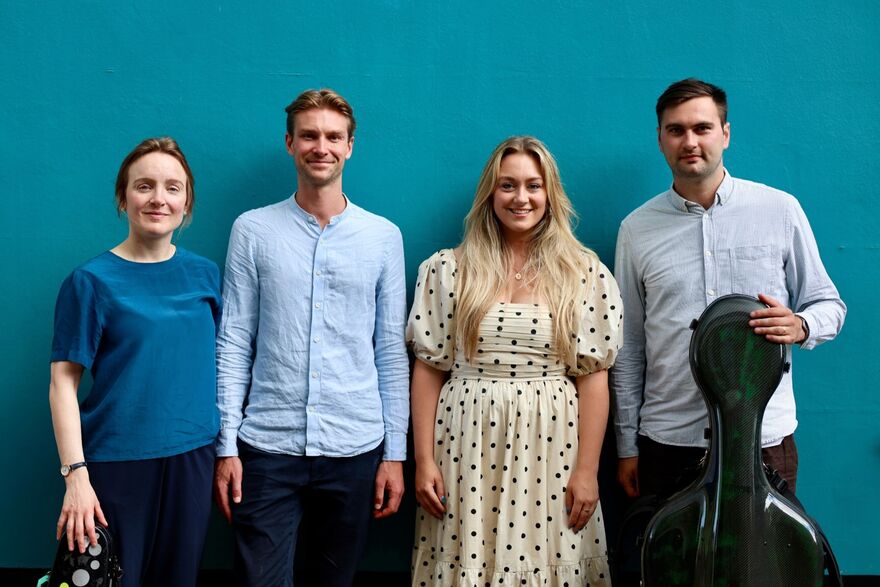 Minerva Baroque standing in front of a blue wall smiling