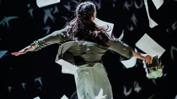 A girls spins mid-dance surrounded by falling paper and confetti