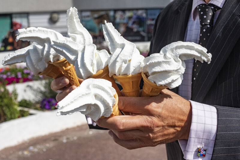 A man in a suit holds 7 Mr Whippy ice creams