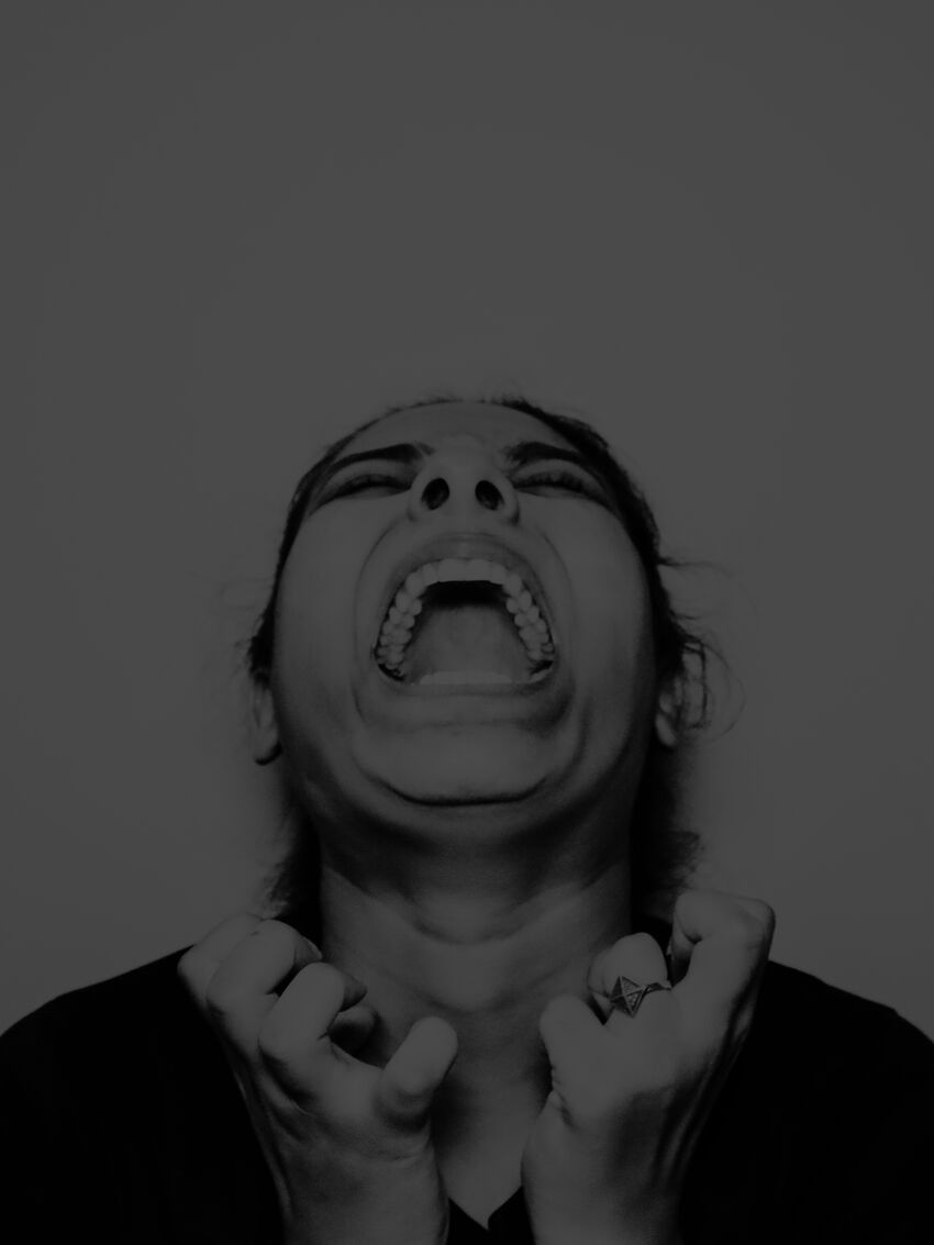 Black and white portrait image of a woman screaming with intensity