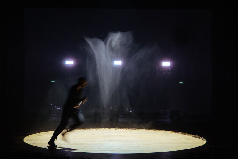 Man running around a bright spotlight with haze and dim lights