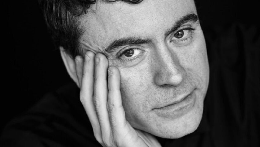 Black & white photo of Paul Lewis, sitting with his head rested on his hand