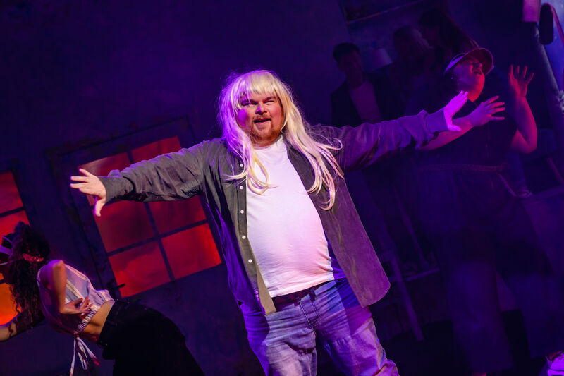 A man wearing a blonde wig and dancing