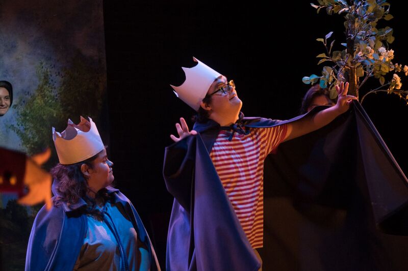 Two actors wearing cape and paper crowns along with stripy t-shirts