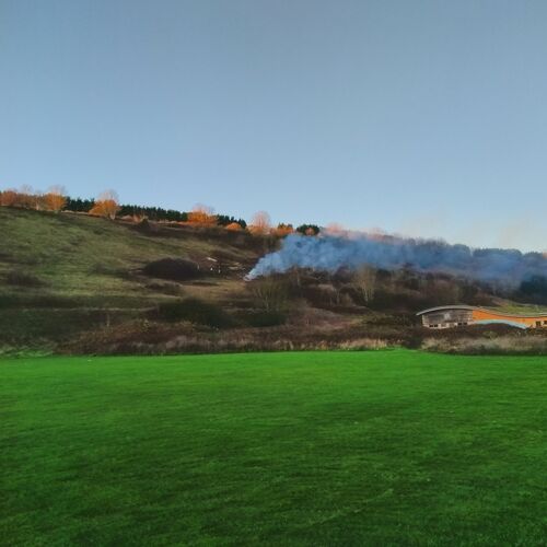 A green field with a hill in the background