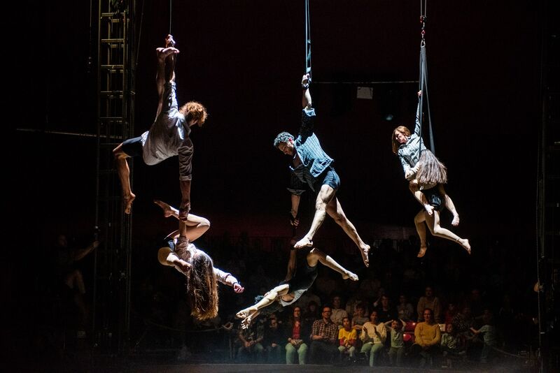 Acrobats suspended from rope and holding other acrobats