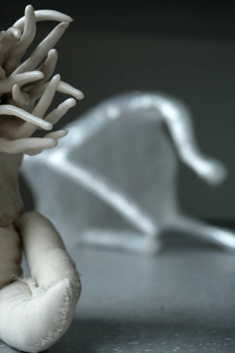 A very close up image of a fabric creature with a blurred miniature chair behind