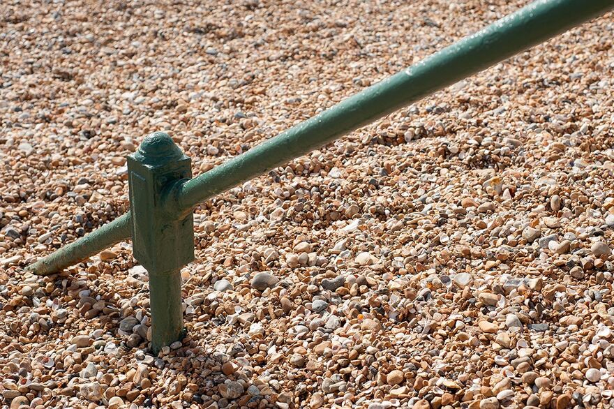 Hand rail covered by pebbles on Brighton beach