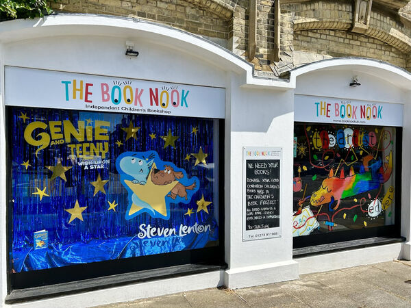 The outside of a children's book shop. There are bright and colourful illustrations in the windows