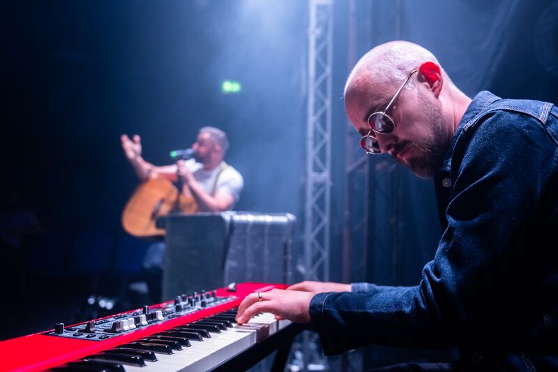 A bald, white man plays a red, white and black keyboard