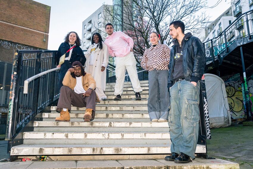 Six young people stand and sit on a curving staircase