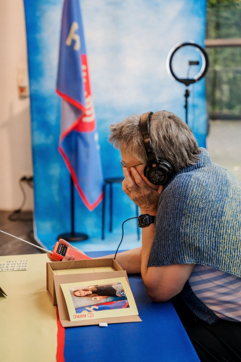Picture of someone sat at a table and listening to a radio