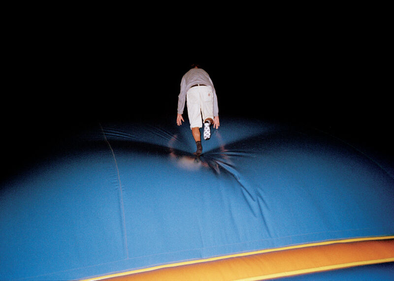 A person in all white walking across a bouncy castle-style floor in the dark