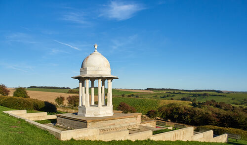 A white dome structure with concrete steps sits amongst fields and trees