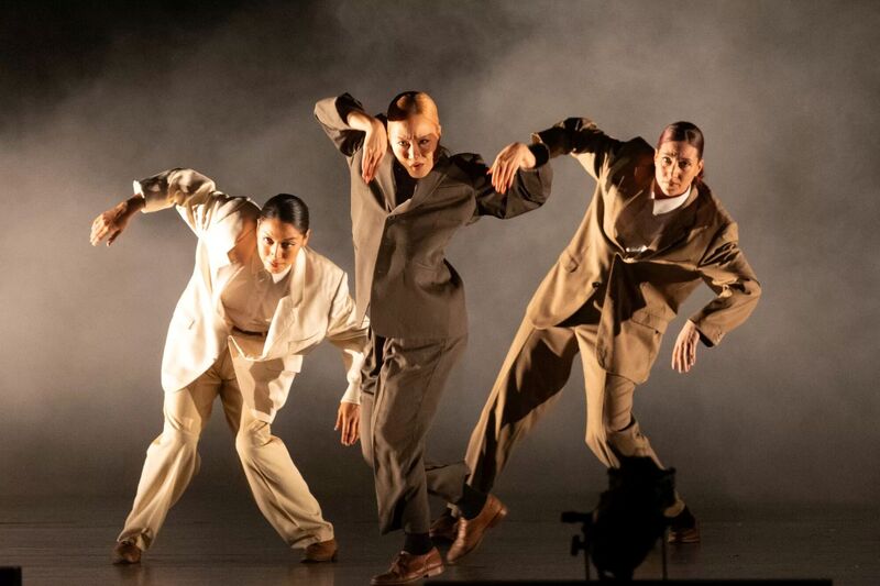 Three dancers on stage wearing oversized suits