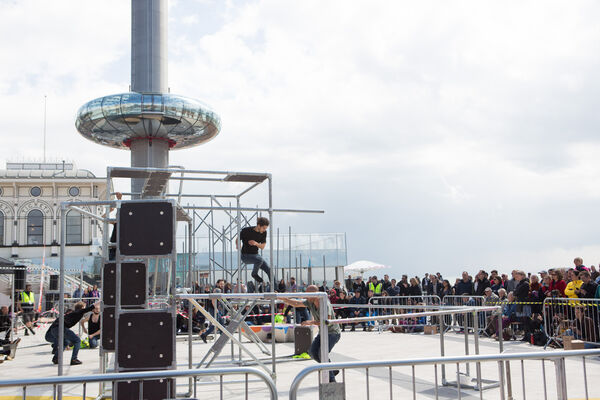 A performance of people moving around small scaffolding, with Brighton beach and i360 behind