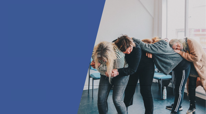A line of four people, bent over so their heads are resting on the person in front of them