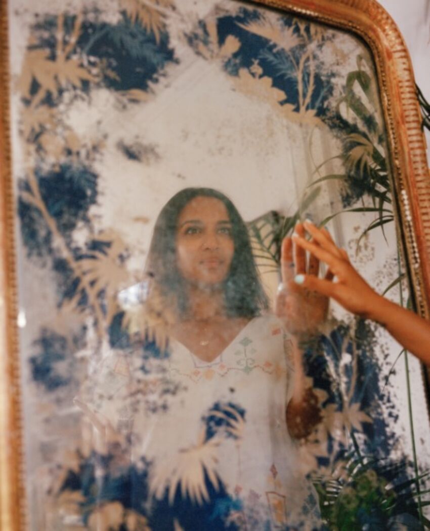 Photograph of Anoushka Shankar touching a mirror showing her reflection