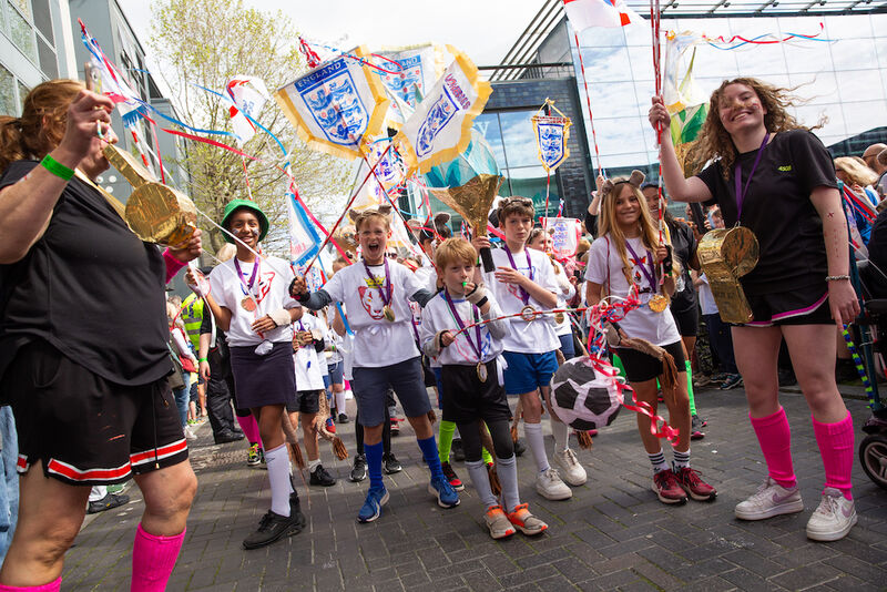 A group of children are dressed as football fans. They have giant whistles and flags
