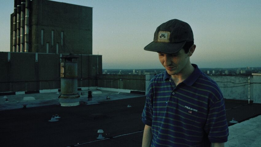 Reuben Bastienne-Lewis wears a Nike cap and looks at the ground smiling slightly