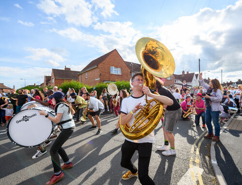 A large outdoor orchestra perform on a sunny day in the street