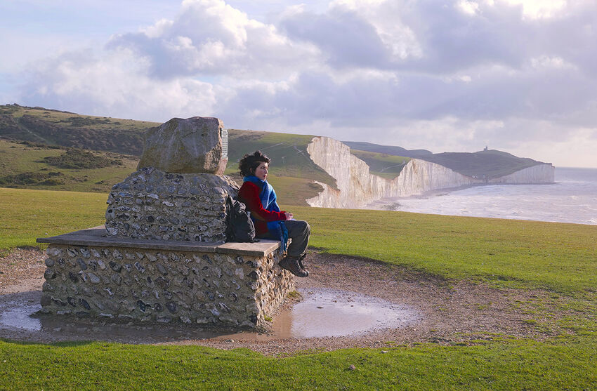 Someone sits on a plinth overlooking the Seven Sisters cliffs
