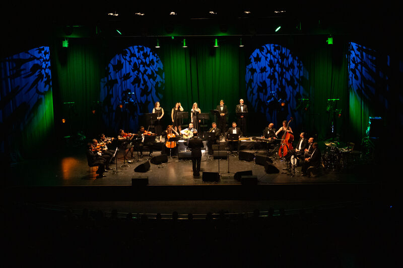Full orchestra against green and blue backdrop