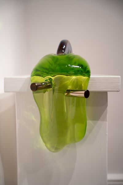 Green slime hangs off a metallic structure, the sculpture sits on a white plinth